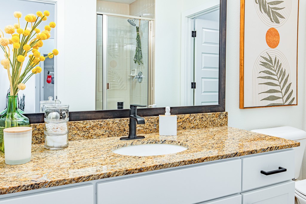 A bathroom with a granite counter top and a sink.
