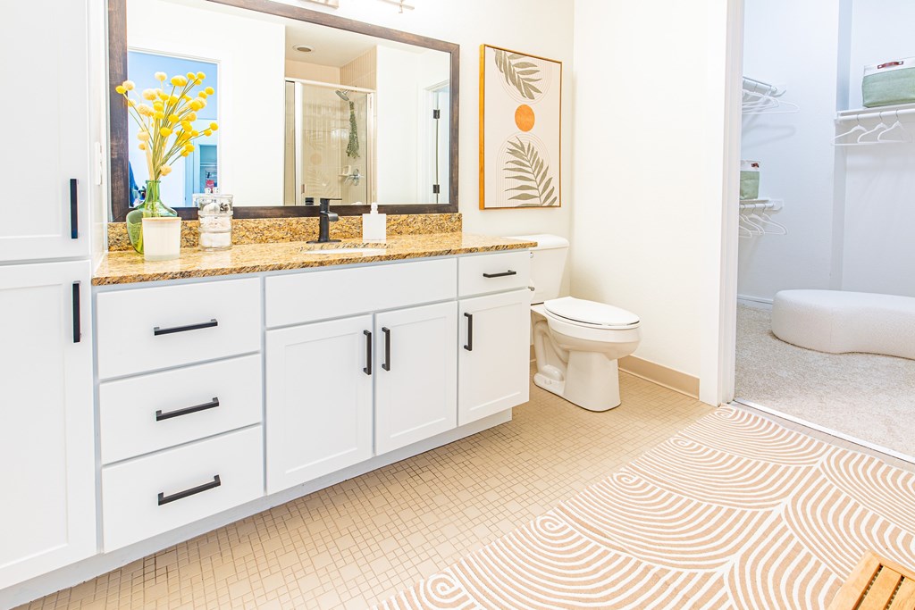A bathroom with a toilet, sink, and cabinets.