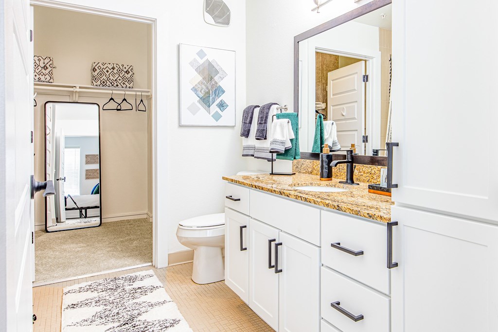 A bathroom with a toilet, sink, and mirror.