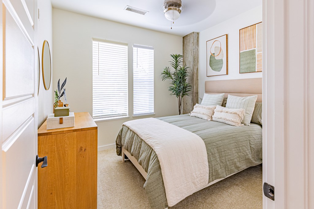 A bedroom with a bed, dresser, and window.