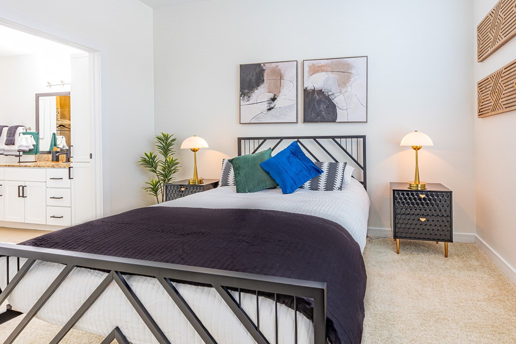 A bedroom with a large bed and two lamps.