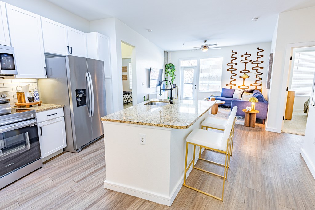 A kitchen with a granite counter top and stainless steel appliances.