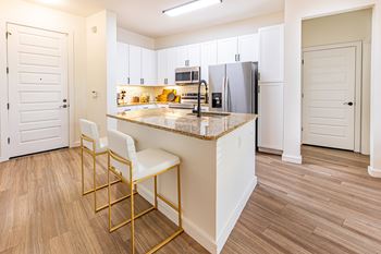 A kitchen with a white island and two white chairs.