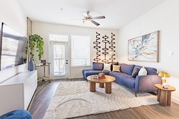 A living room with a blue couch and a white ceiling fan.