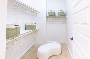 A white laundry room with a white bench and white shelves.