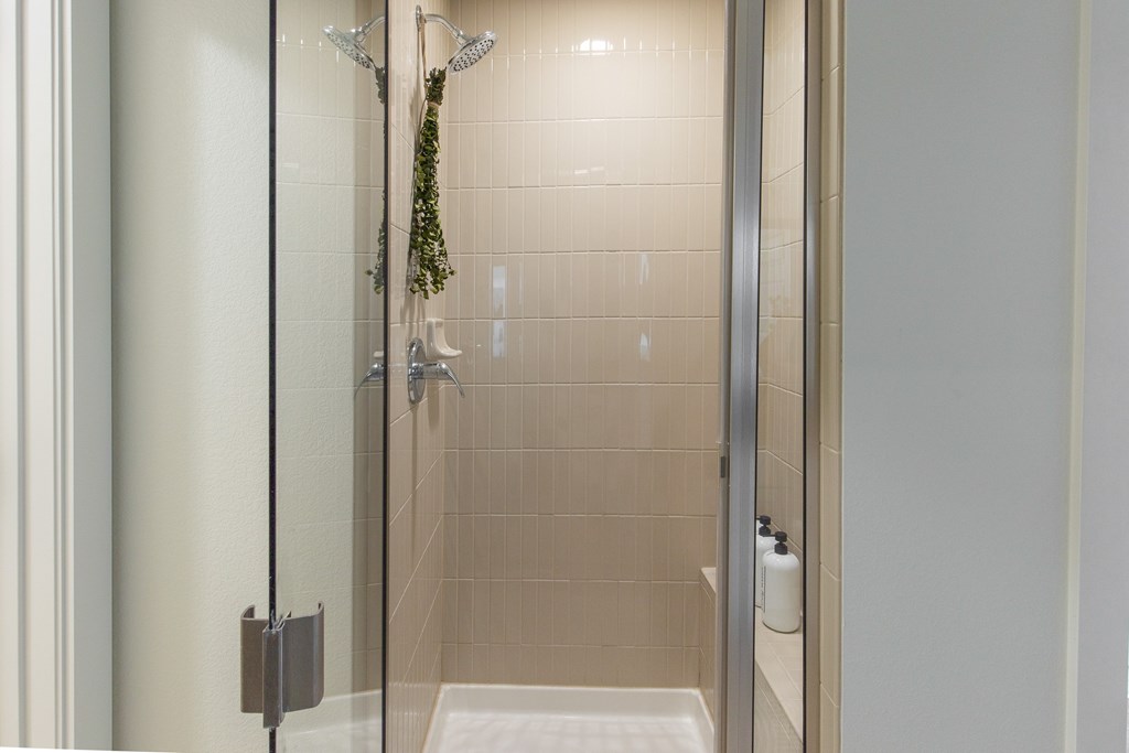 A shower area with a glass door and a white mat on the floor.