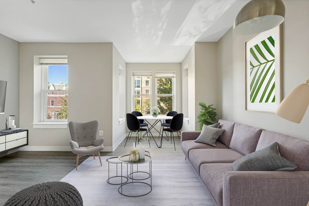 A living room with a grey couch, a white chair, a black chair, a coffee table, and a large painting on the wall.