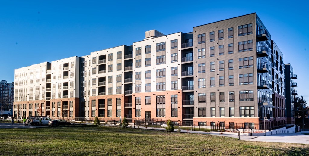 a large apartment building with many windows and a grass field