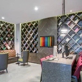 a room with a desk and chairs and a wall of shelves