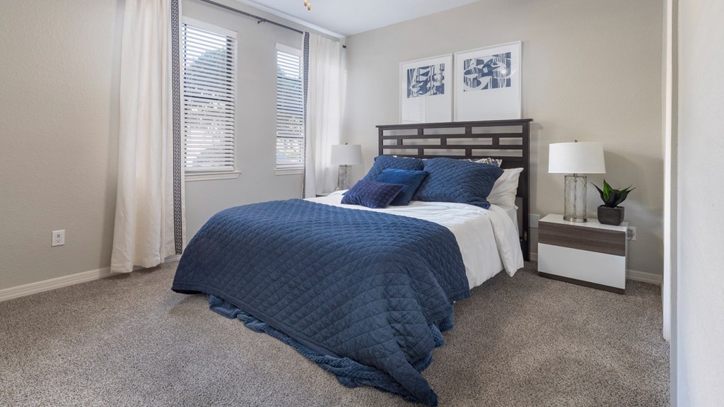 A bedroom with a bed covered in a blue quilted blanket.