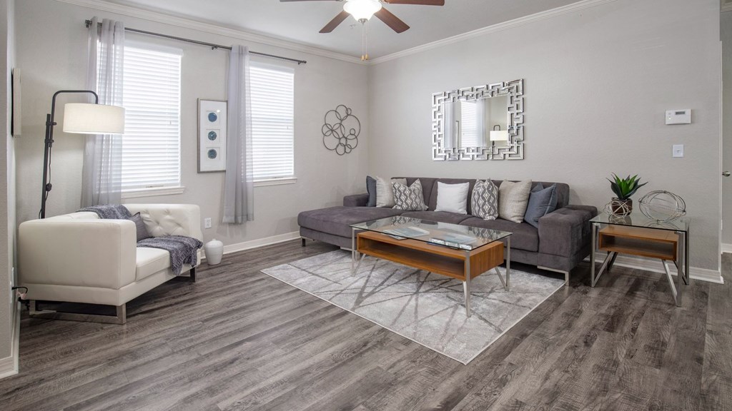 A living room with a white couch, a grey couch, a coffee table, and a ceiling fan.