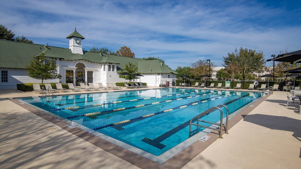 A large swimming pool in front of a white building with a green roof.