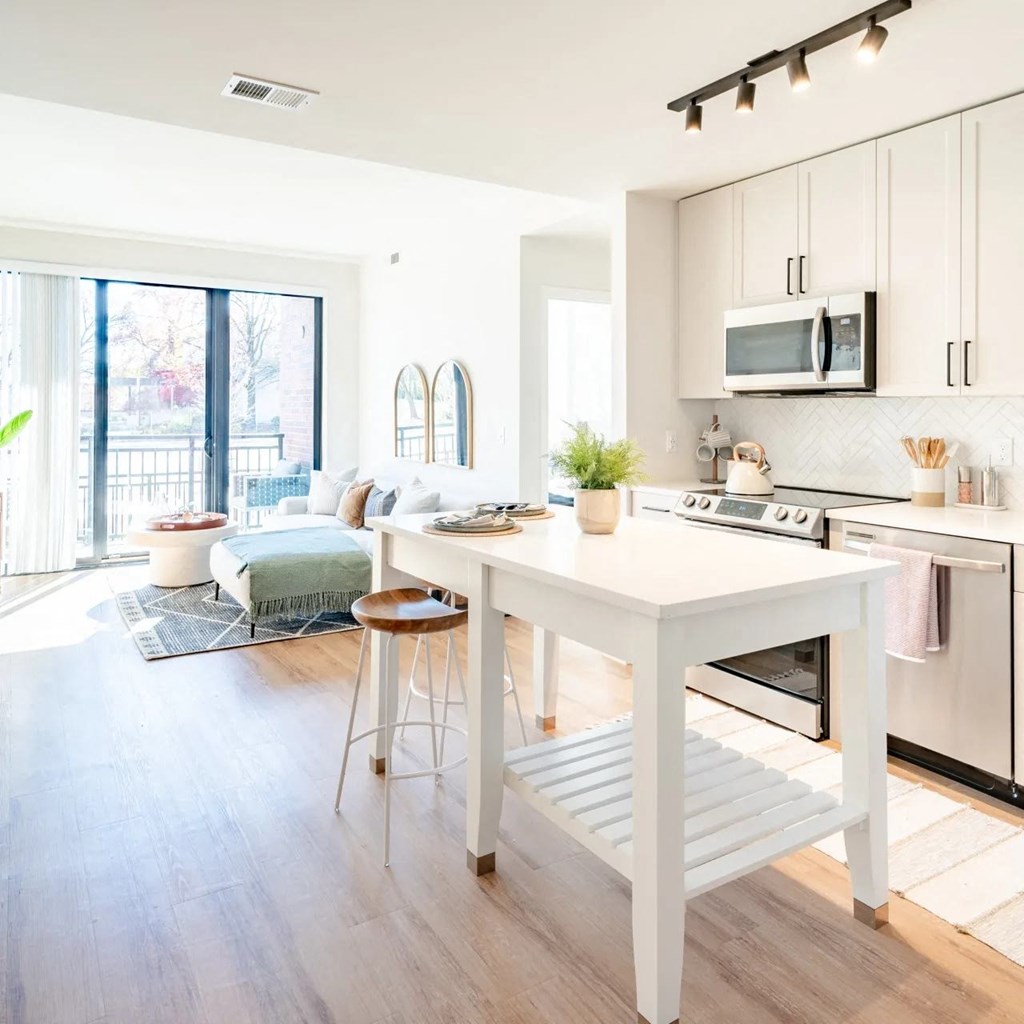 a white kitchen with a white island and a living room