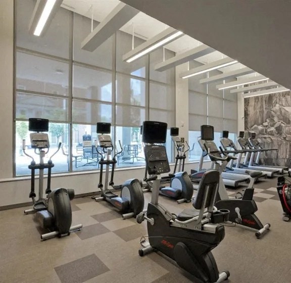 a gym with cardio equipment and a window view of a pool
