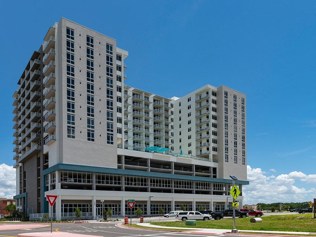 A large, modern building with a parking garage in front.