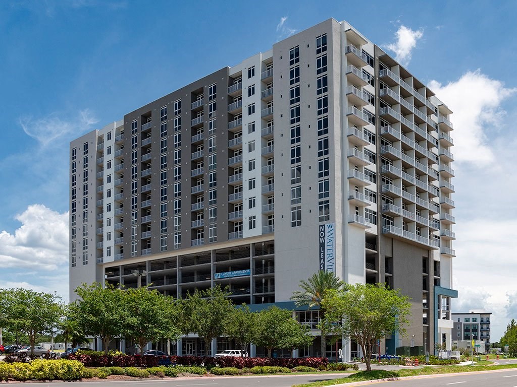 A large, modern apartment building with a parking garage in front.