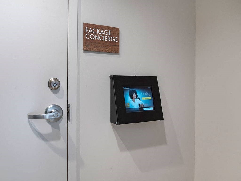 A door with a package concierge sign and a screen on the wall.