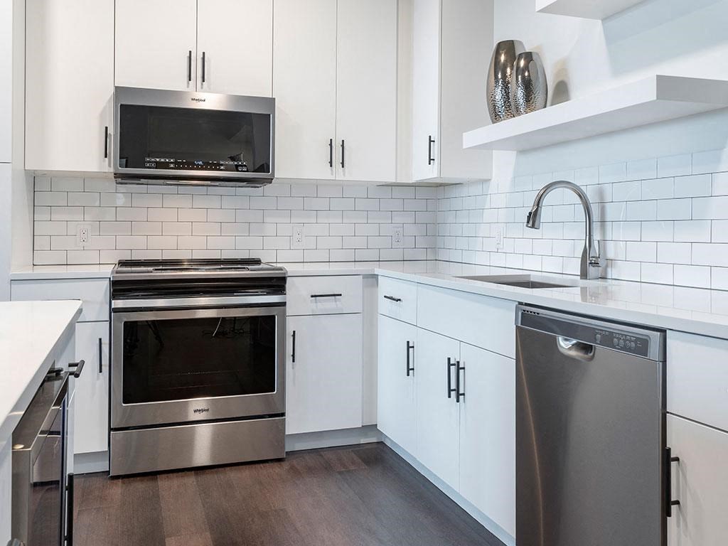 A modern kitchen with white cabinets and stainless steel appliances.