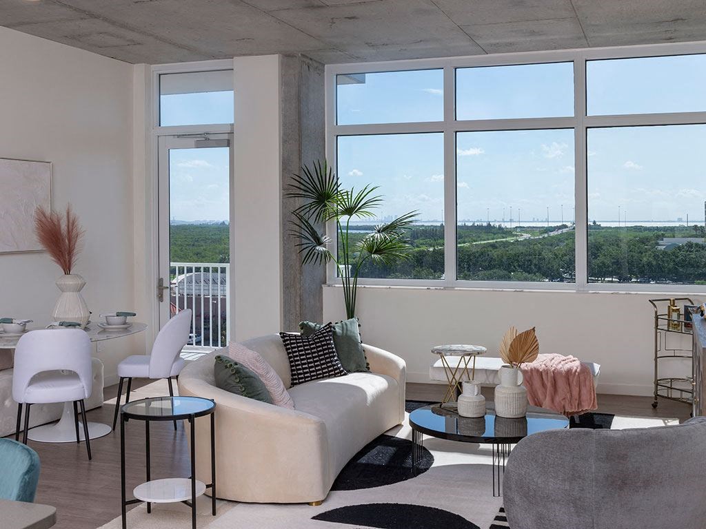 A living room with a white couch and a large window overlooking a landscape.