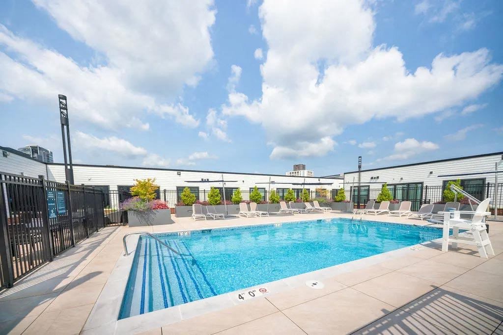 a pool on the roof of a building with chairs around it