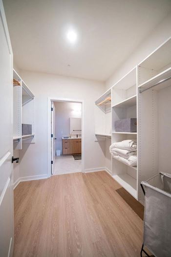 a large walk in closet with a bathroom in the background