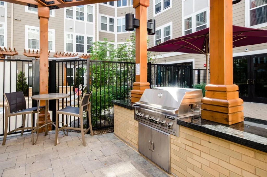 a patio with a grill and a table with chairs