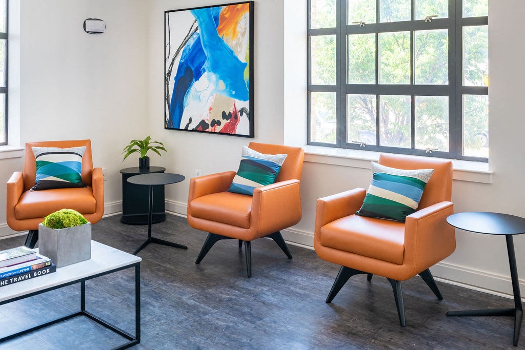 a living room with orange chairs and a table
