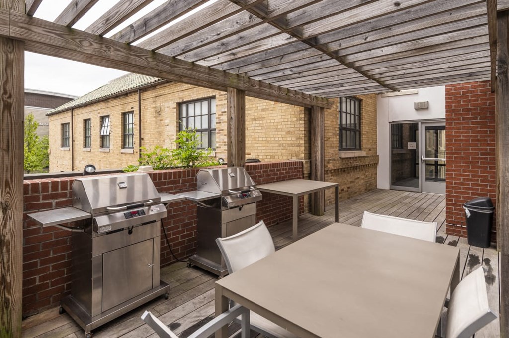 a patio with a barbecue grill and a table with chairs