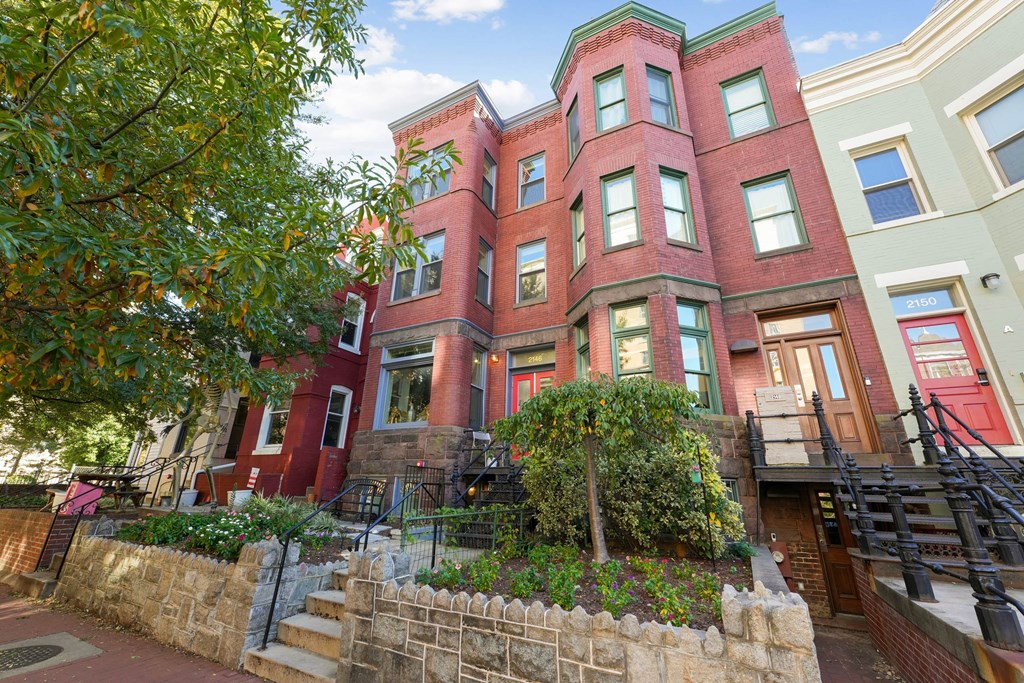 A red brick building with a green tree in front.