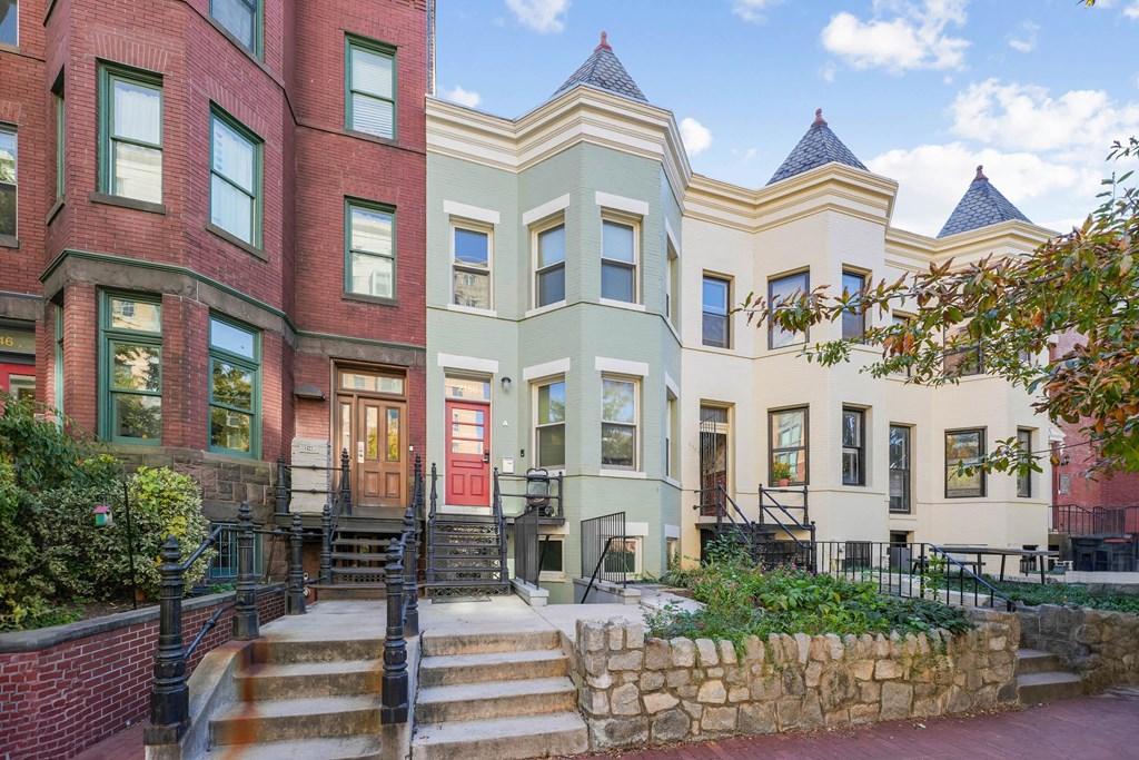 A row of colorful houses with a stone wall in front.
