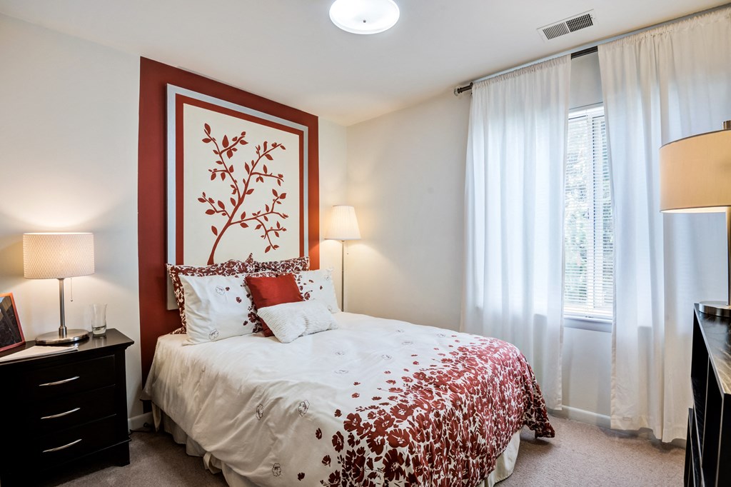 a bedroom with a bed and a red and white comforter