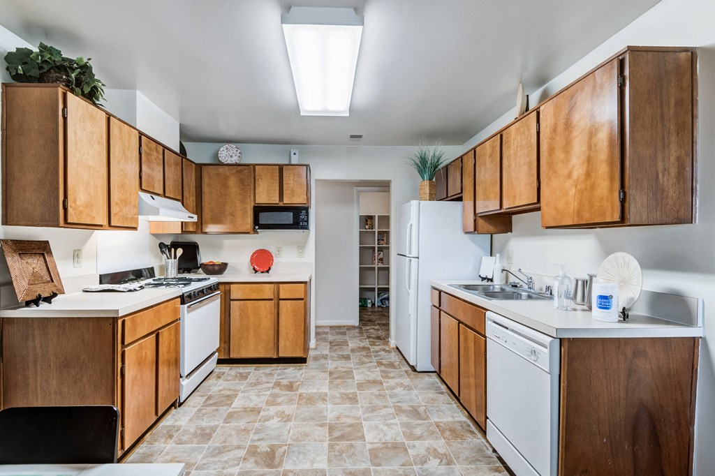 an empty kitchen with white appliances and wooden cabinets