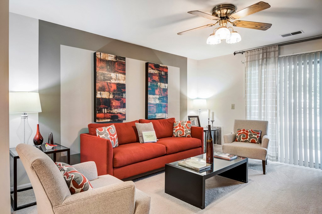a living room with a couch and chairs and a ceiling fan