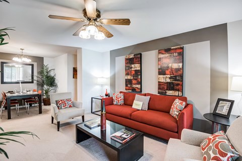 a living room with a red couch and a ceiling fan