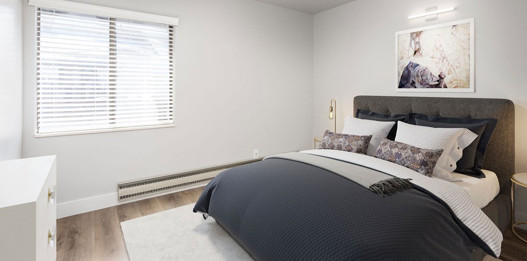 Bedroom with hardwood flooring, white walls, and a window