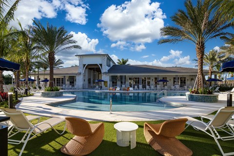 A poolside area with chairs and the clubhouse in the background.