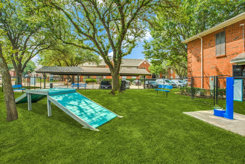 Our on-site dog park offers the perfect space for your furry friends to run, play, and enjoy custom agility features in a shaded, grassy setting.