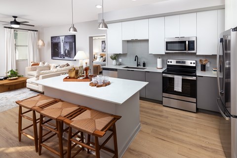 A modern kitchen with a white island and wooden bar stools.