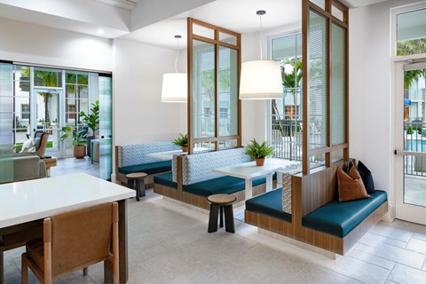 A modern resident lounge with sitting booths with white table and blue cushions.