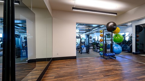 a gym with weights and exercise equipment on a wooden floor