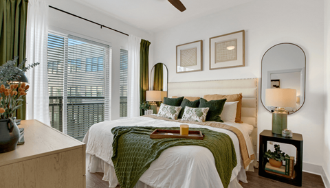 A bedroom with a large bed and a view of a cityscape through the window.