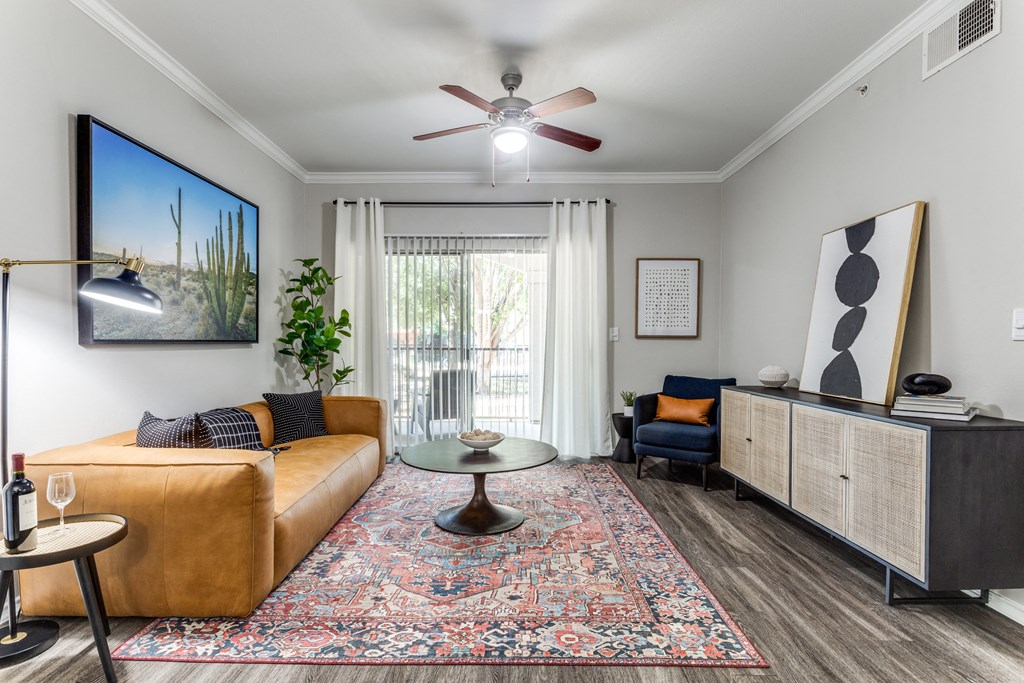 Pet-Friendly Apartments in North Austin, TX - Sycamore Springs - Furnished Living Room with Faux Plank Flooring, a Sliding Glass Door to a Private Patio/Balcony, a Ceiling Fan, and Stylish Decor