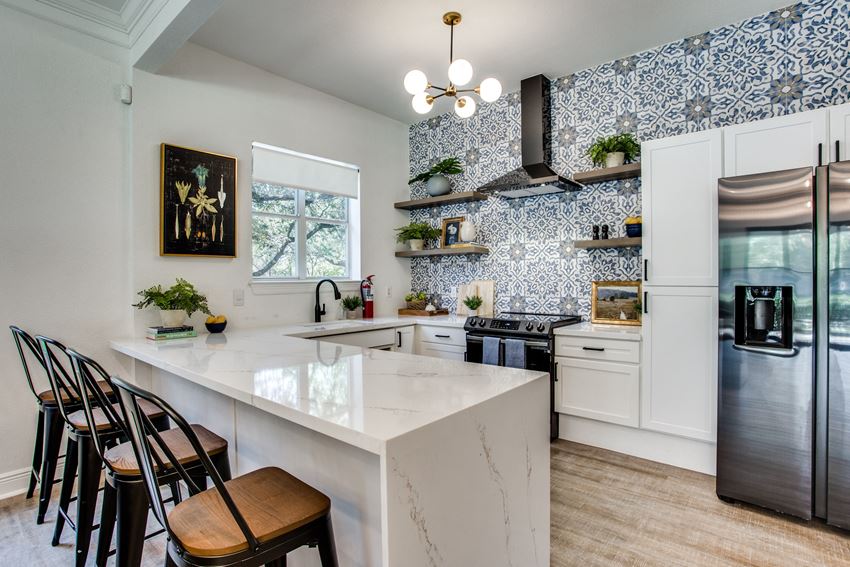a kitchen with a marble counter top and blue and white tiles
