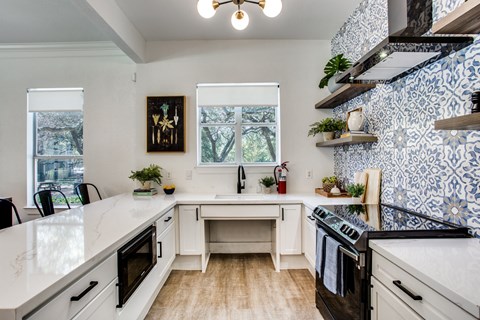 an updated kitchen with blue and white wallpaper and white counter tops