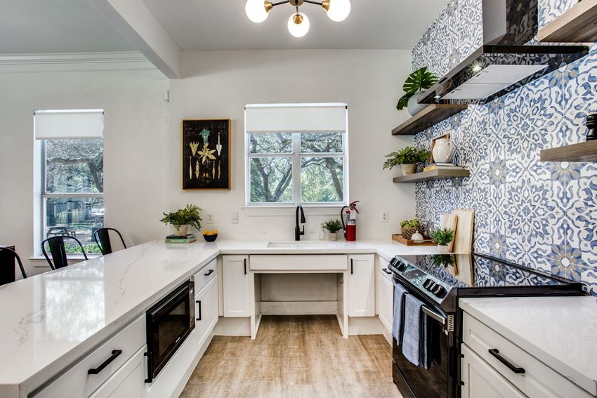 an updated kitchen with blue and white wallpaper and white counter tops