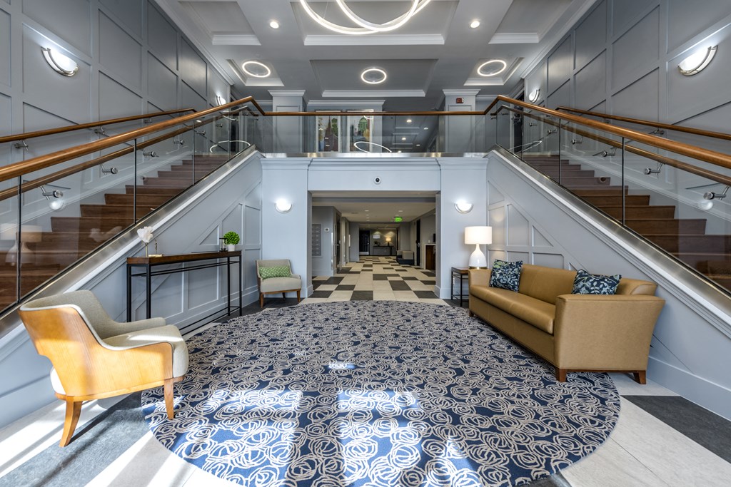 Main entrance into lobby area with seating and two large staircases on each side of the room