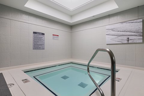 A hot tub in a room with a skylight.