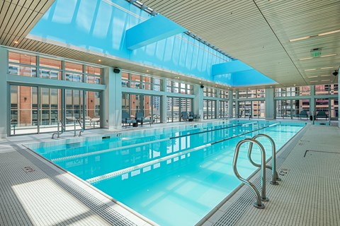 A large indoor swimming pool with a blue tiled floor and a glass ceiling.