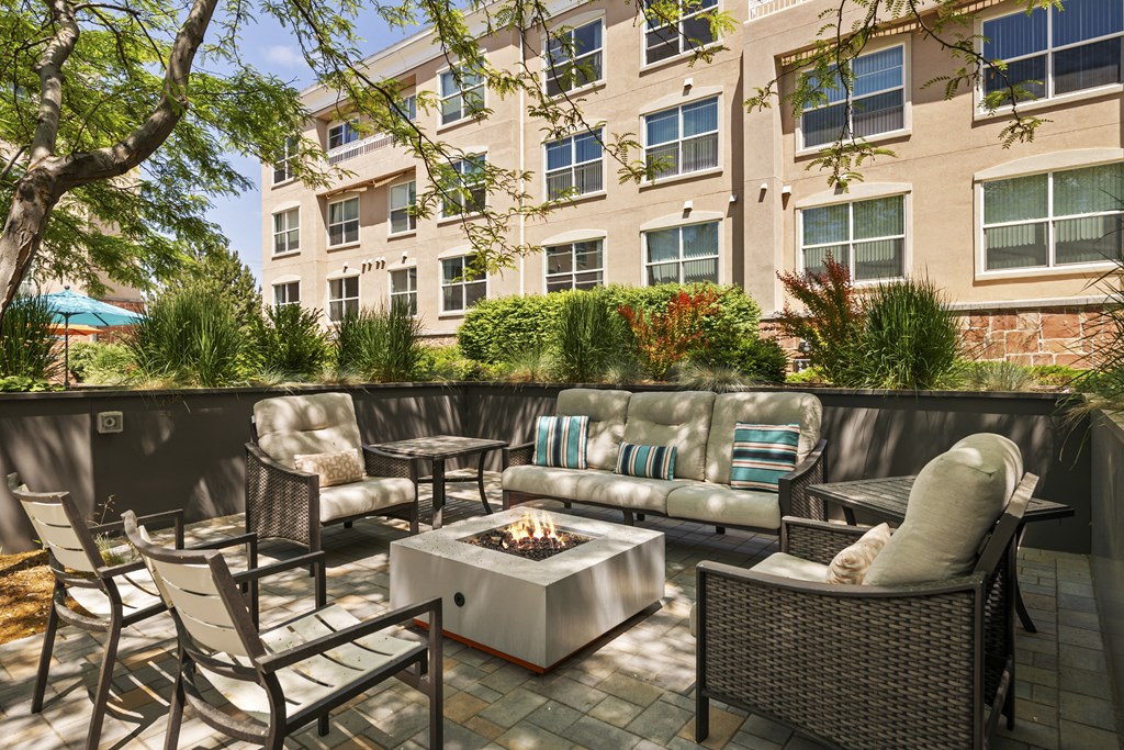 a patio with furniture and a fire pit in front of an apartment building