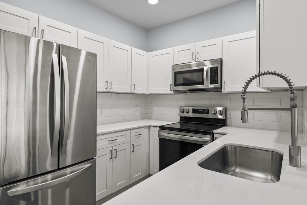 A kitchen with a stainless steel refrigerator, microwave, oven, and sink.